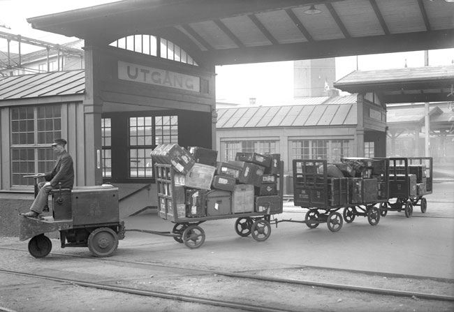 Stockholm Central p 1930-talet. En trehjulig s kallad  "eltraktor" drar ivg med tre stycken plattformsvagnar lastade med polletterat resgods.