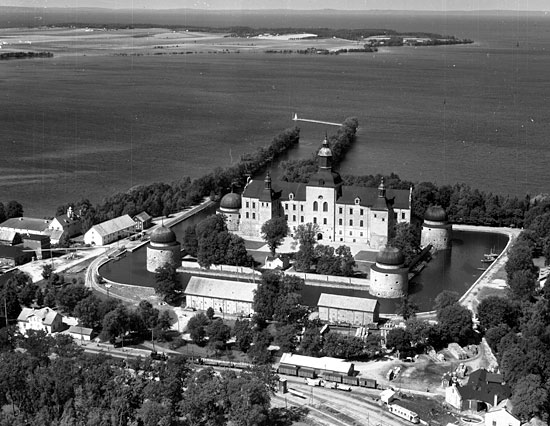 Flygfoto ver Vadstena slott med jrnvgsomrdet i frgrunden. Lngst till vnster syns stationshuset och till hger lokstallet. En rlsbuss syns vid lokstallet. Det r den som trafikerar strckan Vadstena - deshg och ter